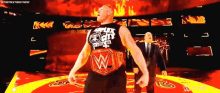 a man in a black tank top with the letter w on it stands in a ring