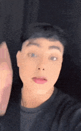 a close up of a young man 's face with a black shirt on
