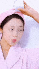 a woman wearing a pink robe and a pink towel wrapped around her head