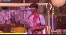 a man with blood on his face is standing in front of clothes hanging on a clothesline ..