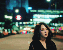 a blurry photo of a woman walking down a street at night with a red light in the background