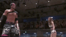 a man is being lifted by a woman in a wrestling ring while a referee watches .