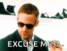 a man wearing sunglasses and a suit is smoking a cigarette and says `` excuse me ? ''
