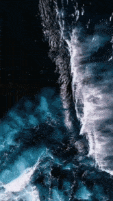 an aerial view of a body of water with waves crashing against a rocky shoreline