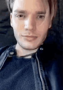 a close up of a man 's face with a leather jacket on .