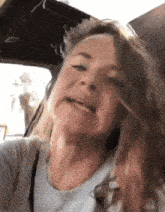 a woman in a car making a funny face with her hair blowing in the wind