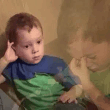 a little boy is sitting in a chair with a man holding his hand to his face .