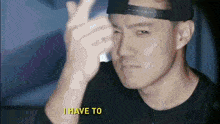 a man wearing a hat and a black shirt is making a peace sign and says i have to