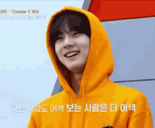 a young man wearing a yellow hoodie is smiling in a foreign language .