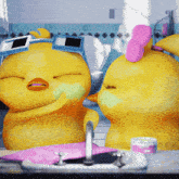 two yellow rubber ducks are standing in front of a sink