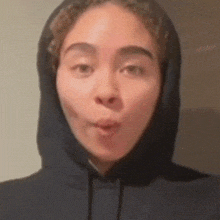 a woman wearing a black hoodie making a face