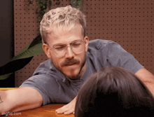 a man with glasses and a mustache is sitting at a table with a woman .