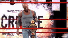 a man in a wrestling ring holding a belt with the word impact behind him