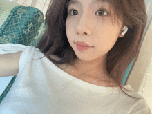 a woman wearing a white shirt and white ear buds looks at the camera