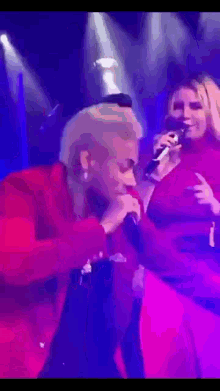 a woman in a red jacket is singing into a microphone on stage