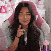 a woman in a hello kitty shirt is sitting in a pink chair and pointing