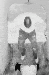 a black and white photo of a man in a white shirt sitting on a toilet