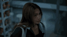 a woman with long hair is walking down a street with a backpack .