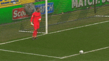 a soccer goalie stands in front of a score match building supplies sign