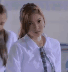 a woman in a white shirt and tie is standing in a classroom .