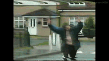 a man stands in front of a house with his arms up