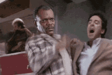 two men are fighting each other in a room .