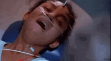 a woman is laying in a hospital bed with a oxygen mask on her face .