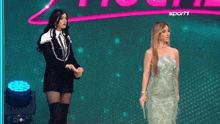 two women standing on a stage with the word sport1 in the background