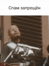 a man with a beard is holding a gun in front of a window with the words spam written on the bottom