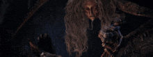 a witch with long hair and a clawed hand is standing in the dark