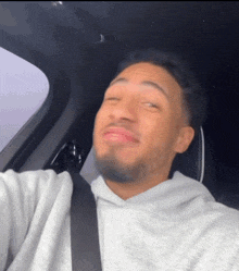 a man wearing a seat belt is taking a selfie in his car