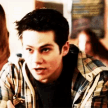 a young man in a plaid shirt is talking to another man