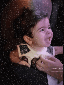 a baby is being held in someone 's arms with the words photolab-it.com on the bottom right