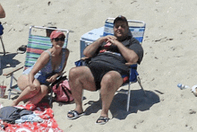 a man and a woman are sitting in beach chairs on the sand