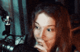 a woman with a nose ring is looking at something in front of a microphone