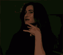 a woman wearing a black shirt and a necklace with a cameo on it looks surprised