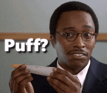a man holding a piece of paper with the word puff written on it