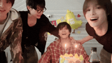 a group of young men are gathered around a birthday cake