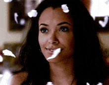a woman is smiling with feathers falling around her