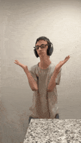 a young man wearing headphones and glasses is standing on a counter