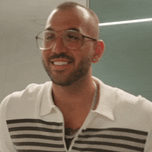 a man wearing glasses is smiling and wearing a striped shirt