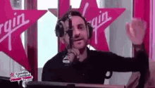 a man is wearing headphones and standing in front of a microphone in a radio station .