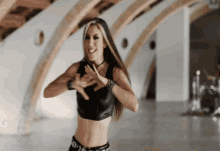 a woman wearing a black crop top and black pants is dancing