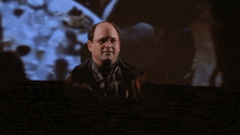 a man wearing glasses is standing in front of a screen with a picture of the moon on it