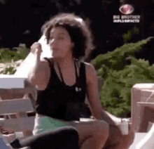 a woman in a black tank top is sitting on a bench holding a napkin in her hand .
