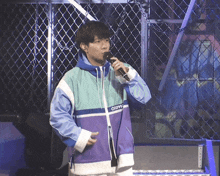 a man singing into a microphone wearing a jacket that says converse