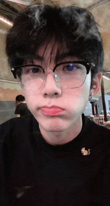 a young man wearing glasses and a black shirt making a face