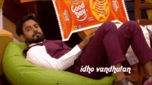 a man is laying on a bean bag chair with a bag of good day cookies behind him