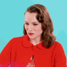 a woman wearing a red coat and red lipstick is making a face .