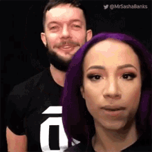 a man and a woman with purple hair are posing for a picture together .
